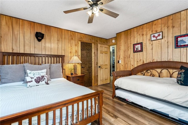 bedroom with a textured ceiling, wood finished floors, and a ceiling fan