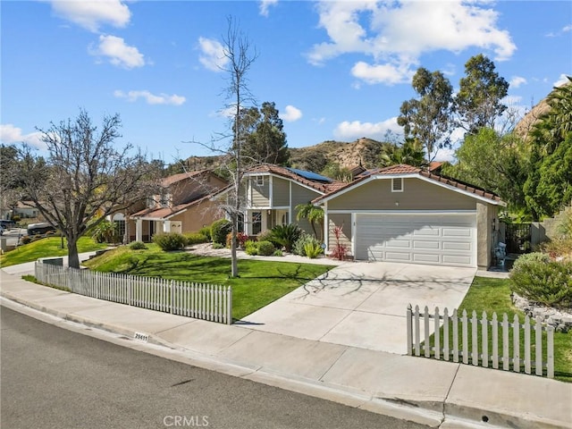 view of front of property featuring a front yard, driveway, solar panels, a garage, and a fenced front yard