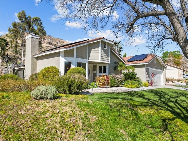 mid-century inspired home with stucco siding, an attached garage, a front yard, solar panels, and a chimney