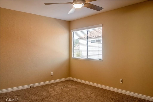 carpeted spare room featuring baseboards and a ceiling fan