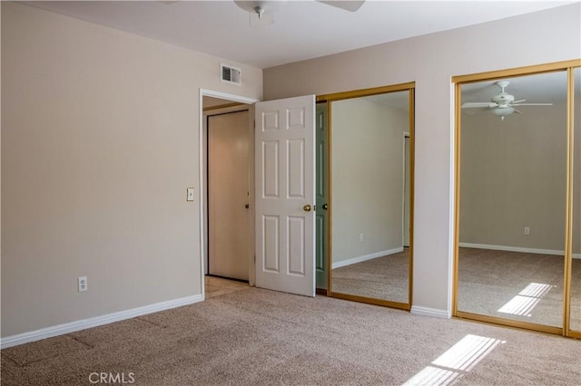 unfurnished bedroom featuring visible vents, multiple closets, carpet floors, and baseboards