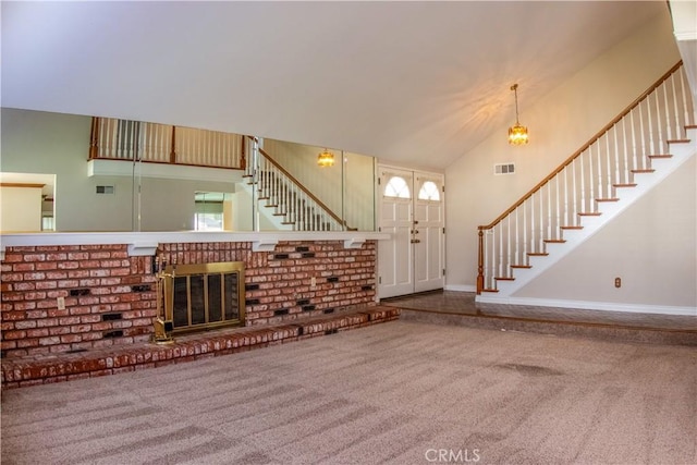 carpeted entrance foyer with stairs, a brick fireplace, visible vents, and high vaulted ceiling