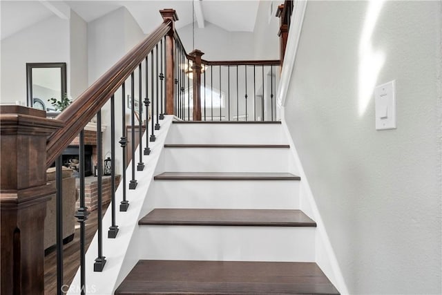 stairs featuring wood finished floors and vaulted ceiling with beams