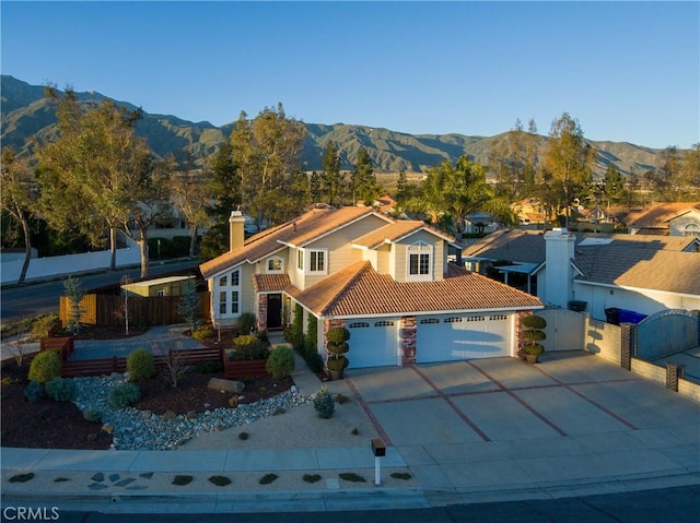 mediterranean / spanish-style home featuring a gate, fence, driveway, a tiled roof, and a mountain view