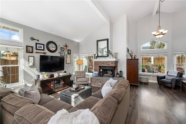 living area with beamed ceiling, a fireplace, wood-type flooring, and a healthy amount of sunlight