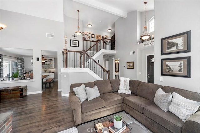 living area featuring baseboards, visible vents, dark wood finished floors, beam ceiling, and stairs