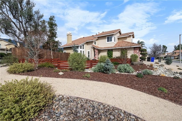 view of home's exterior with a tiled roof and fence