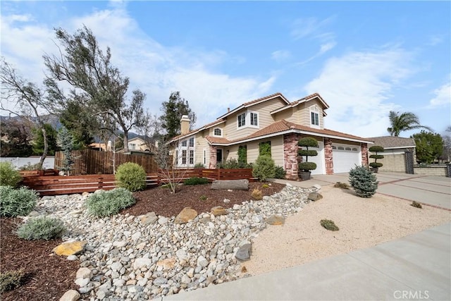 view of front facade with driveway, a tile roof, a garage, and fence