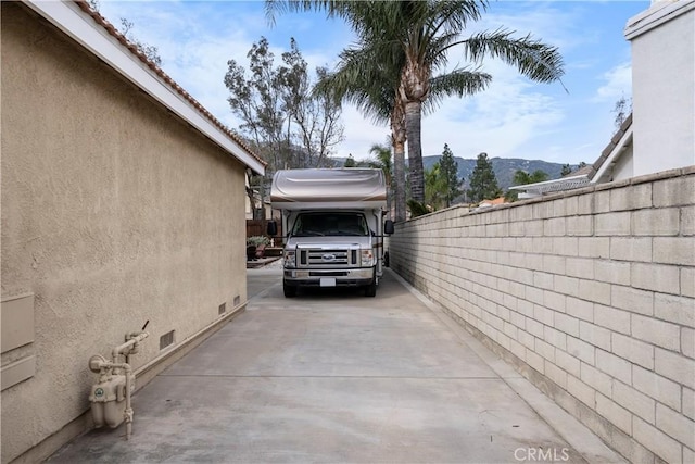 view of car parking with a mountain view and fence