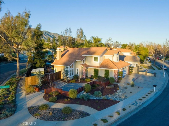 view of front of home with a mountain view, concrete driveway, and fence