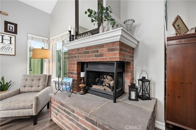 living room with vaulted ceiling, a fireplace, and wood finished floors