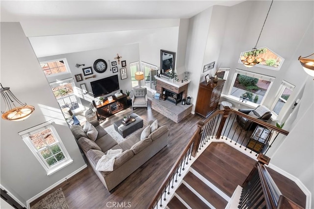 living room with high vaulted ceiling, stairs, baseboards, and wood finished floors