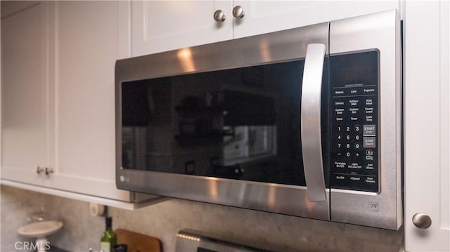 room details with white cabinetry, stainless steel microwave, and mail area