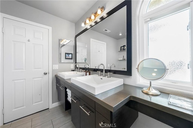 bathroom with double vanity, visible vents, and a sink