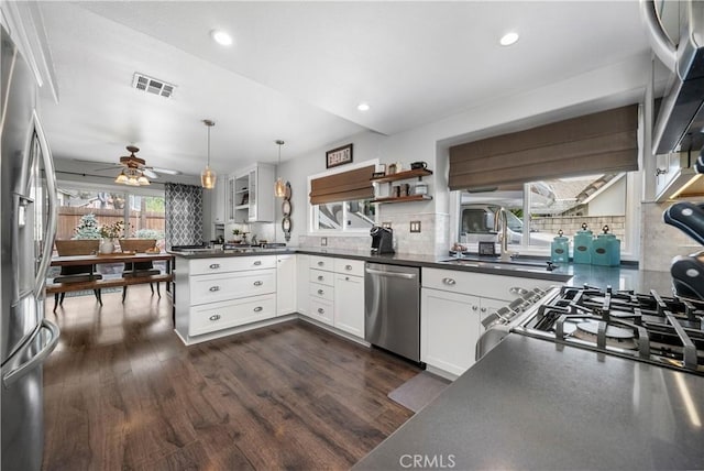 kitchen with dark countertops, visible vents, open shelves, stainless steel appliances, and a sink