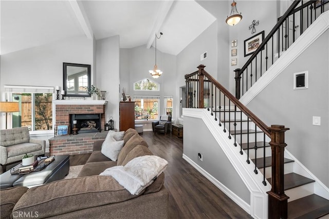 living area featuring dark wood-style floors, visible vents, beam ceiling, stairs, and a brick fireplace