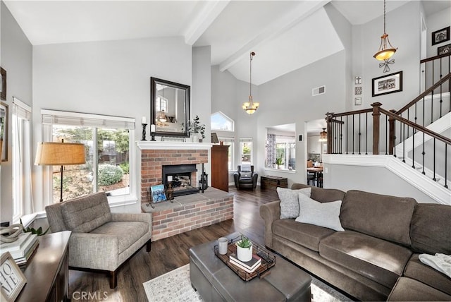 living area featuring visible vents, a brick fireplace, dark wood-type flooring, beamed ceiling, and stairway