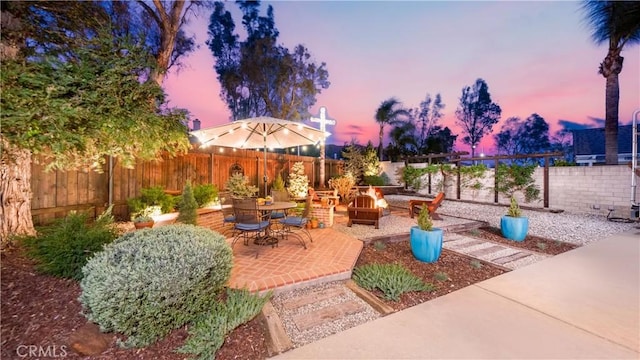 patio terrace at dusk featuring a fire pit and a fenced backyard