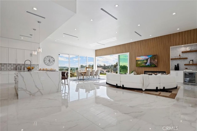 living area with recessed lighting, wooden walls, marble finish floor, and beverage cooler