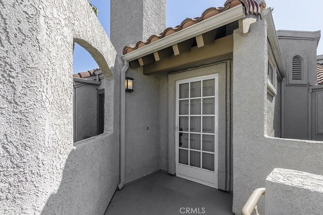 property entrance featuring stucco siding and a tiled roof