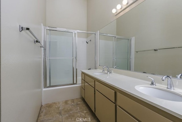 full bath featuring double vanity, combined bath / shower with glass door, and a sink