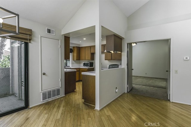 kitchen with visible vents, stainless steel microwave, light countertops, and light wood-style floors