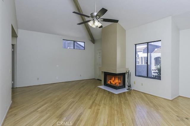 unfurnished living room with a multi sided fireplace, vaulted ceiling with beams, light wood-type flooring, and a ceiling fan