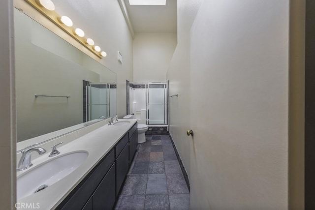 bathroom featuring a sink, toilet, stone tile floors, and double vanity