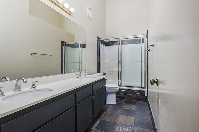 bathroom with stone tile flooring, a shower stall, and a sink