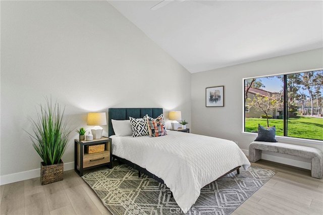 bedroom featuring baseboards, wood finished floors, and vaulted ceiling