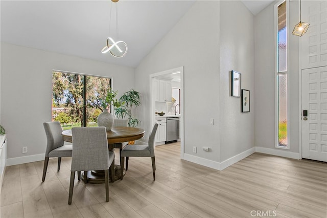 dining area featuring baseboards, light wood-style flooring, high vaulted ceiling, and an inviting chandelier