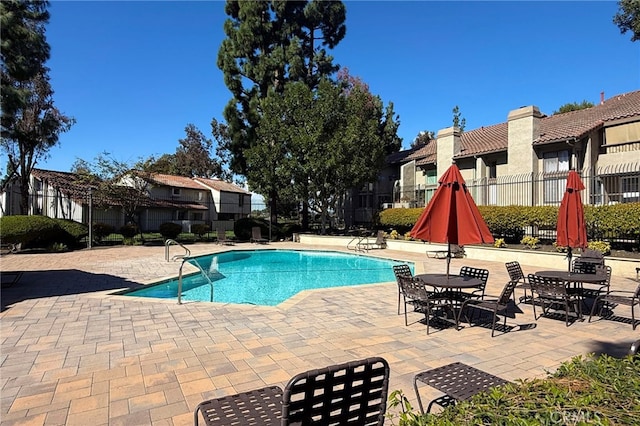 community pool featuring a patio area, fence, and a residential view