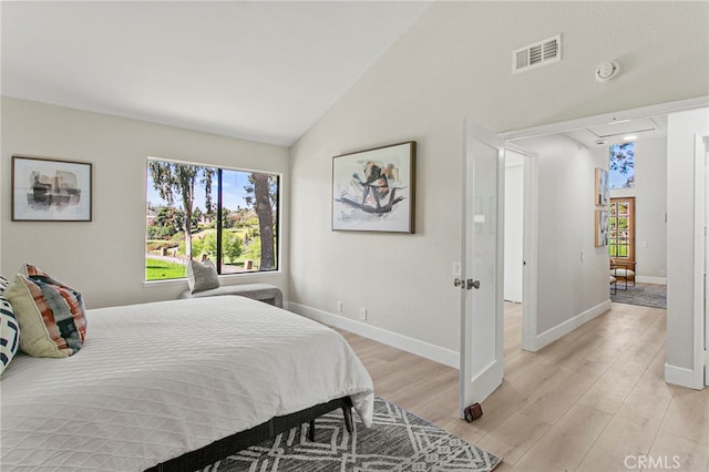 bedroom with visible vents, high vaulted ceiling, light wood-style floors, baseboards, and attic access