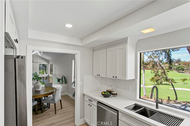 kitchen featuring stainless steel appliances, a sink, light countertops, light wood-style floors, and white cabinetry