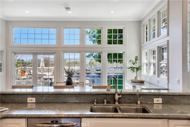 kitchen with visible vents, a sink, crown molding, white cabinetry, and stainless steel dishwasher