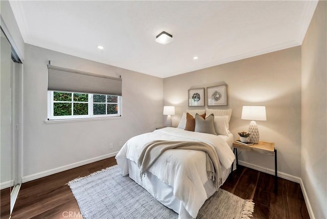 bedroom featuring baseboards, wood finished floors, and crown molding