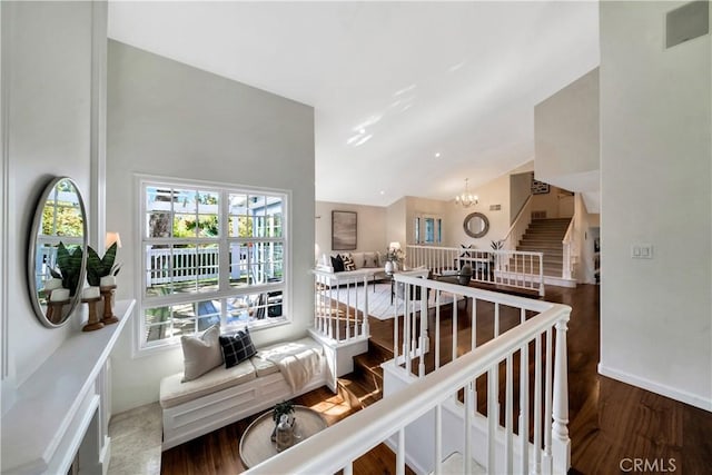 stairs with an inviting chandelier, wood finished floors, baseboards, and lofted ceiling