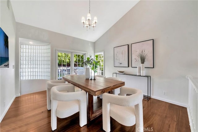 dining room featuring a chandelier, baseboards, high vaulted ceiling, and wood finished floors