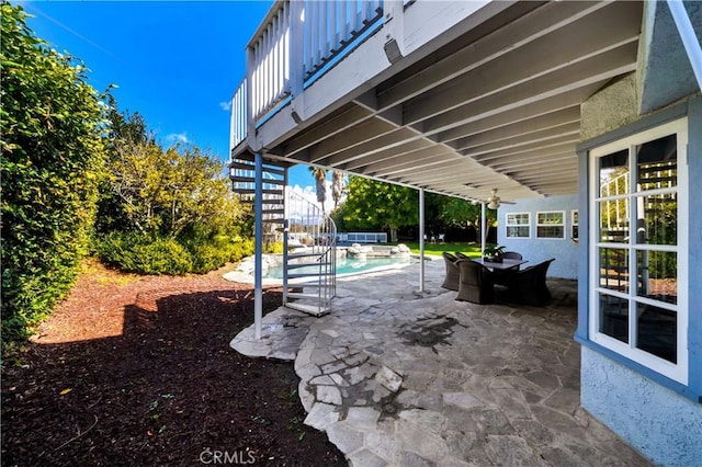 view of patio / terrace featuring an outdoor pool and stairs