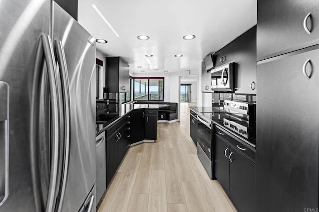 kitchen with dark countertops, light wood finished floors, stainless steel appliances, and dark cabinets