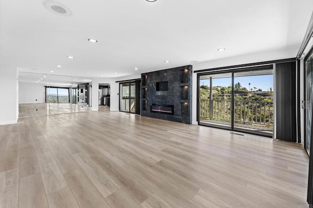 unfurnished living room with recessed lighting, light wood-style flooring, a fireplace, and visible vents