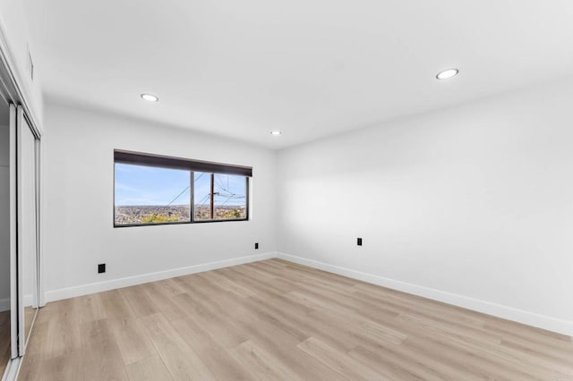 unfurnished bedroom featuring recessed lighting, light wood-style floors, baseboards, and a closet