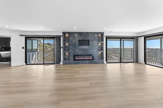 unfurnished living room featuring wood finished floors, a healthy amount of sunlight, and a premium fireplace