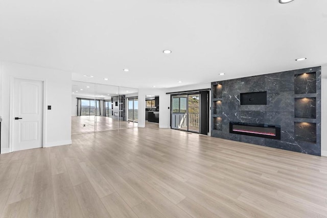 unfurnished living room featuring wood finished floors, recessed lighting, a fireplace, and baseboards