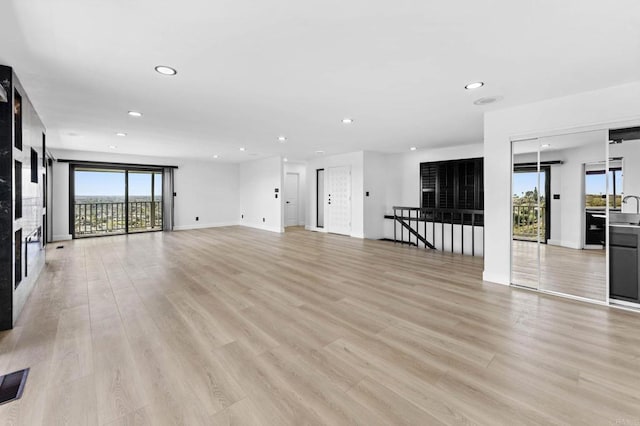 unfurnished living room with visible vents, recessed lighting, light wood finished floors, a premium fireplace, and baseboards