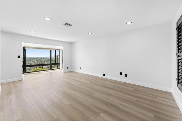 empty room with visible vents, recessed lighting, light wood-type flooring, and baseboards