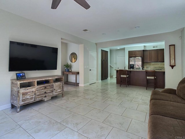 living room featuring visible vents, baseboards, and a ceiling fan