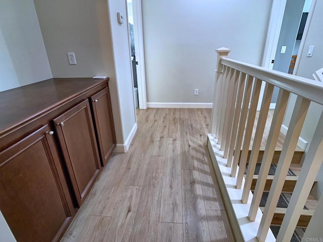 corridor featuring light wood-style floors and baseboards