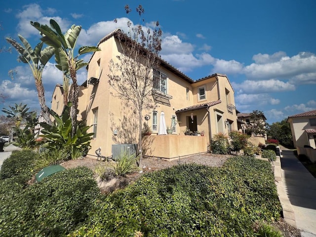 view of side of home with a tile roof and stucco siding