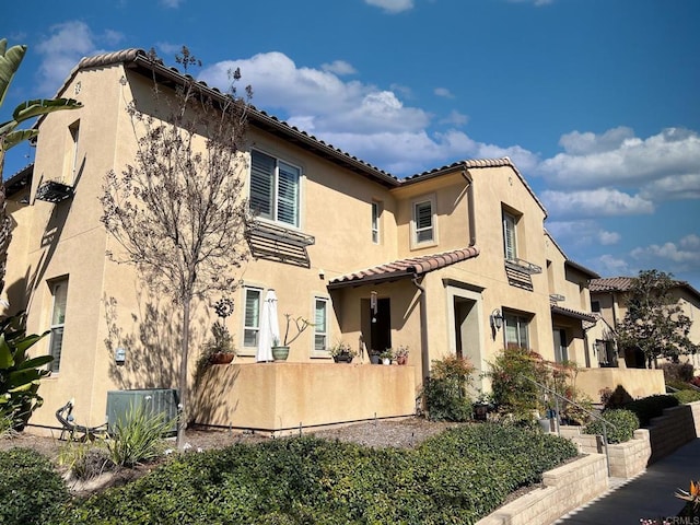 back of property with stucco siding and a tile roof